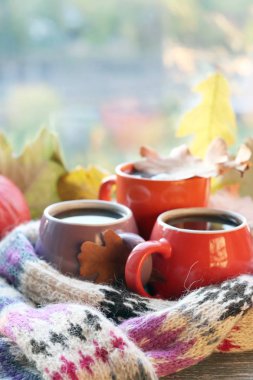 Üç fincan kahve, balkabağı, yapraklar, arka planda yün bir eşarp, ev konforu, aile, Şükran Günü, sonbahar sezonu