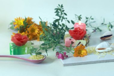 Doğal sabun, mumlar, tuz, taze çiçekler, arka planda deniz kabukları, spa tedavileri, mevsimsel sağlık, vücut bakımı, rahatlama.