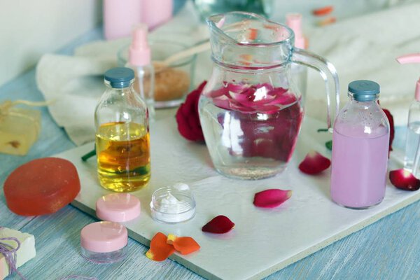 Fresh roses, petals, water and oil on the table for the preparation of natural cosmetics, spa treatments, healthy lifestyle