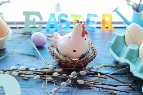 Easter decoration, toy chicken, eggs, pussy-willow twigs on a wooden windowsill, spring, festive home decor