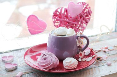 Cup of coffee with meringues and marshmallows, hearts, illumination on a wooden windowsill, home comfort, St. Valentine's Day
