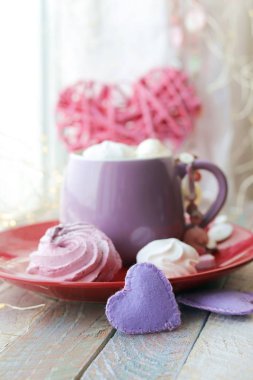 Cup of coffee with meringues and marshmallows, hearts, illumination on a wooden windowsill, home comfort, St. Valentine's Day