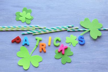 Parlak harflerden Patrick, dekoratif yonca folyo yaprakları yeşil arka planda kokteyl kamışları, üst manzara.