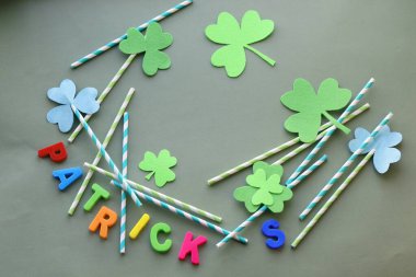 Parlak harflerden Patrick, dekoratif yonca folyo yaprakları yeşil arka planda kokteyl kamışları, üst manzara.