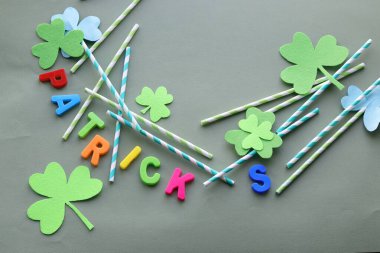 Parlak harflerden Patrick, dekoratif yonca folyo yaprakları yeşil arka planda kokteyl kamışları, üst manzara.