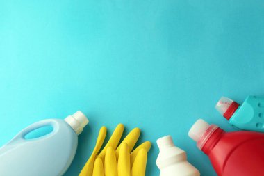 Plastik şişelerde sıvı deterjanlar, mavi arka planda evi temizlemek için lastik eldivenler, üst manzara.