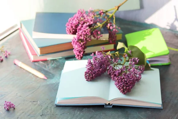 Books, open notebook for notes, lilac flowers on the table, the concept of home schooling, comfortable at home, education