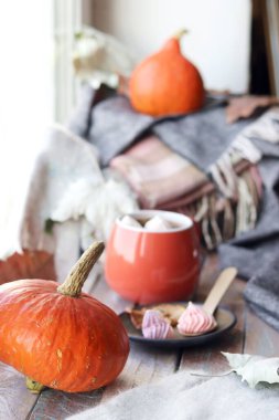 Bir fincan kahve, krema, balkabağı, yapraklar, arka planda ekose, ev konforu, Şükran Günü, sonbahar sezonu