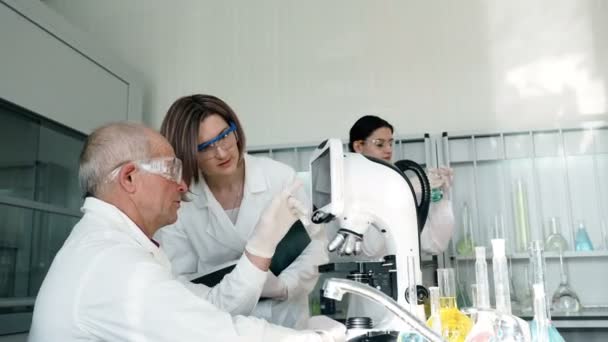 Las personas trabajan en laboratorio clínico con microscopio — Vídeo de stock