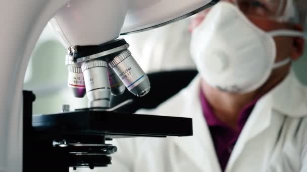 Investigador científico trabaja con microscopio en laboratorio — Vídeo de stock