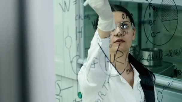 Femme en laboratoire écrire la formule sur le panneau de verre — Video