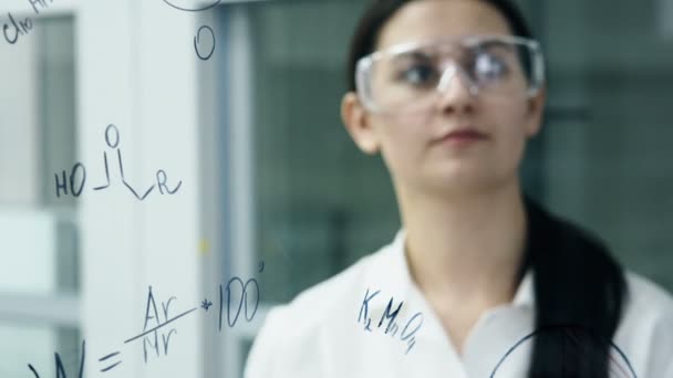 Mujer en laboratorio escribir fórmula en el tablero de vidrio — Vídeos de Stock