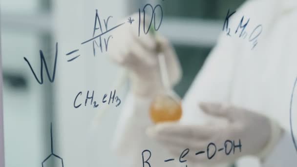 Femme en laboratoire écrire la formule sur le panneau de verre — Video