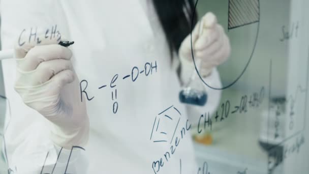 Femme en laboratoire écrire la formule sur le panneau de verre — Video