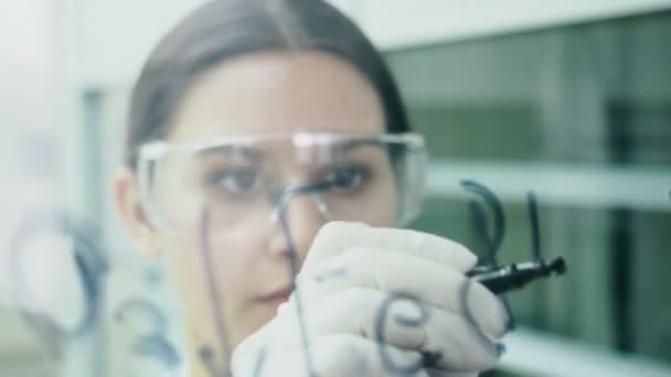 Femme en laboratoire écrire la formule sur le panneau de verre 