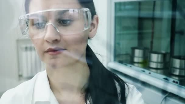 Žena v laboratoři napsat vzorec na skleněné desce — Stock video