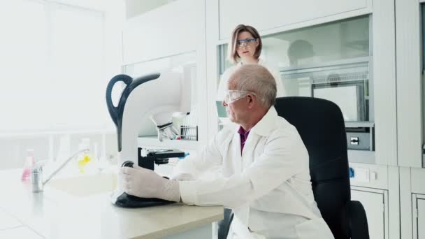 Doctor con colega hacer experiencia por microscopio — Vídeos de Stock