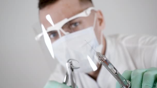 Portret van gemaskerde tandarts specialist met tandheelkundig gereedschap en spuit in handen pov — Stockvideo