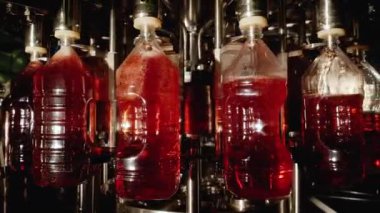Batch of plastic bottles passes through the conveyor and is filled with liquid.