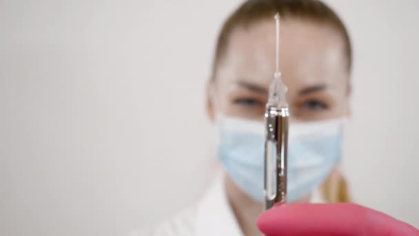 Masked female dentist with dental tools in hand and release of drug from syringe — Stock Video