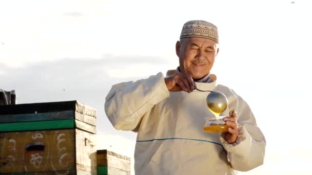 Portret van de oude Aziatische boer man of lachende senior giet honing in container — Stockvideo