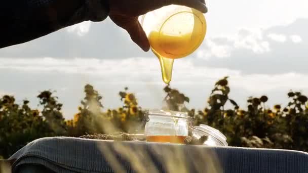 Madu emas mengalir ke dalam wadah kaca, memproduksi makanan organik atau alami — Stok Video