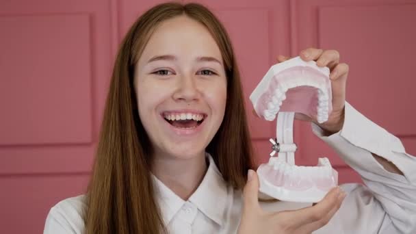 Portrait of a young girl smiling and laughing, clicking an implant in her jaw. — Stok video