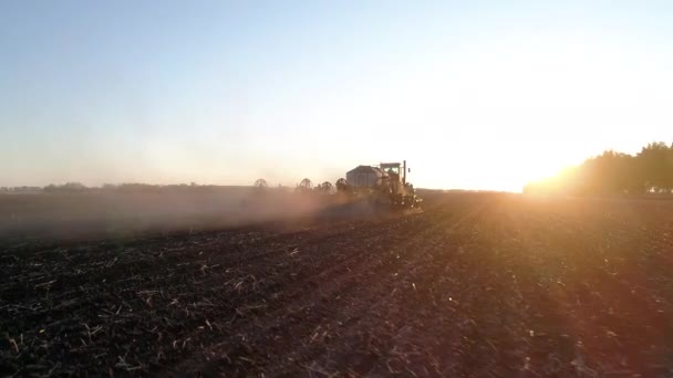 Landbouwwerkzaamheden op het platteland met machines of trekker bij zonsondergang, op een natuurboerderij — Stockvideo