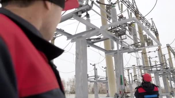 Arbeten inom tung industri som utförs av energiarbetare på elektrisk utrustning i kraftverk — Stockvideo