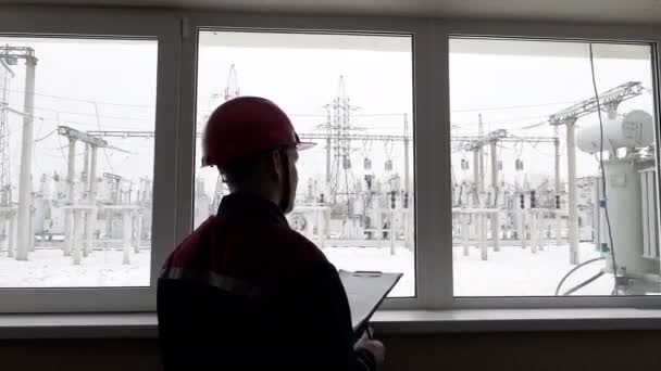Inżynier przemysłowy w bezpiecznym twardym kapeluszu pisze plan pracy na obiekcie — Wideo stockowe