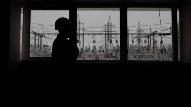 Silhouette by window of engineer plans work process by talkie on power industry — Stockvideo