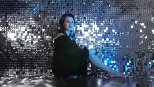 Портрет краси моди усміхнена молода жінка сидить на підлозі в неоновому світлі — стокове відео