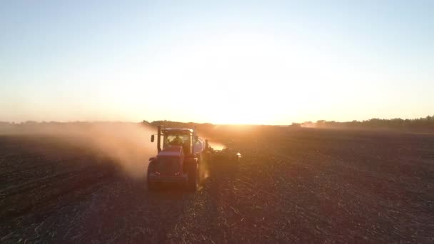 Industria de las obras rurales en el campo en la granja en la puesta del sol por la máquina agrícola o tractor — Vídeos de Stock