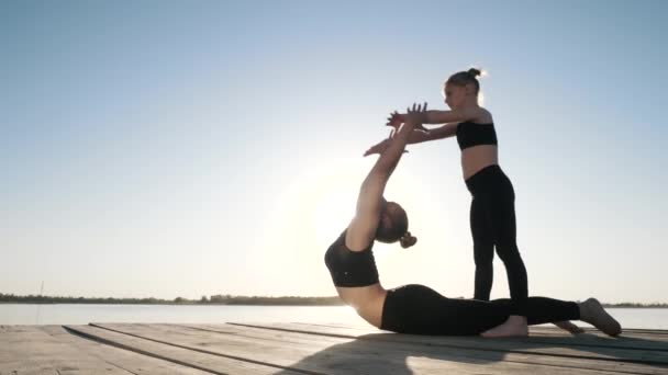 İki küçük kız çift esneme hareketleri yapıyor, dışarıda yoga alıştırması yapıyorlar. — Stok video