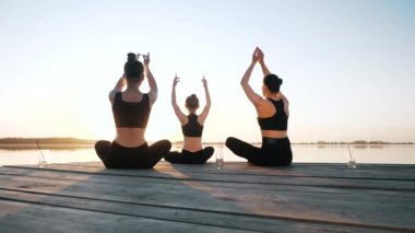 Grup kızı yoga egzersizi yapıyor, meditasyon yapıyor Lotus pozisyonunda birlikte oturuyor.