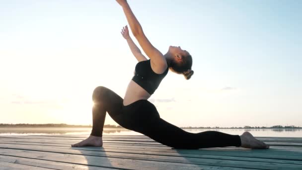 Esnek genç kız yoga yapıyor, esneme pozisyonu sergiliyor, vücudunu rahatlatıyor. — Stok video