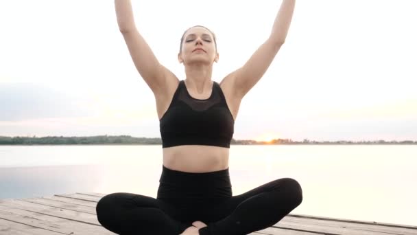 Yoga yapan kadın, Lotus pozisyonunda oturup meditasyon yapıyor, vücudunu rahatlatıyor. — Stok video
