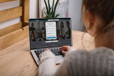 laptop yüklü LinkedIn sayfa ile birlikte oturan kız Resim kırpılmış