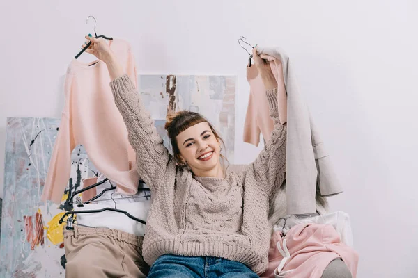 Lachende Meisje Zittend Een Fauteuil Hangers Met Kleding Bedrijf Handen — Stockfoto