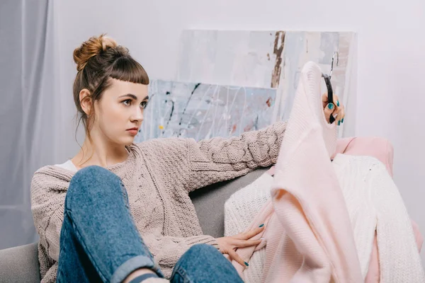 Girl Sitting Armchair Skeptically Looking Sweater Hanger — Free Stock Photo