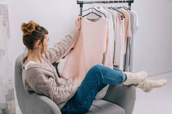 Vista Lateral Menina Sentada Poltrona Olhando Para Camisa Mão — Fotografia de Stock Grátis