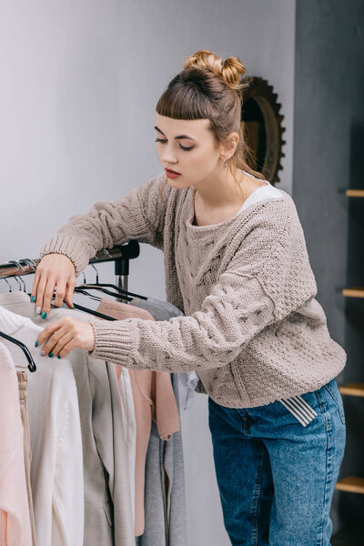 girl standing near stand and choosing what to wear