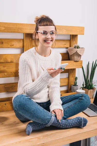 Sorrindo Menina Sentada Mesa Escritório Segurando Smartphone Olhando Para Câmera — Fotografia de Stock