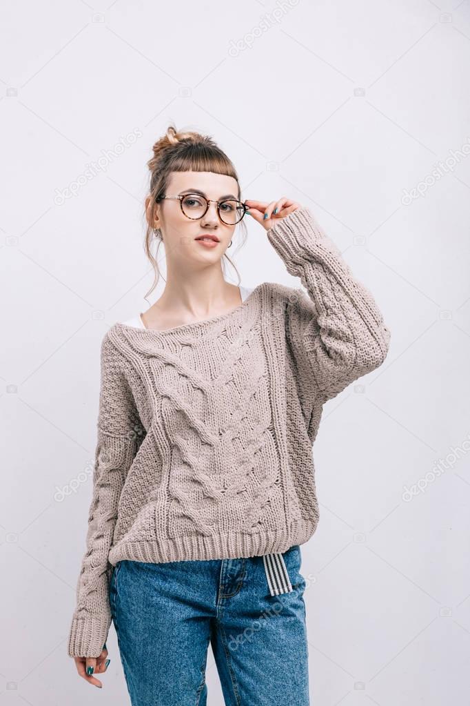 beautiful girl standing and touching glasses isolated on white