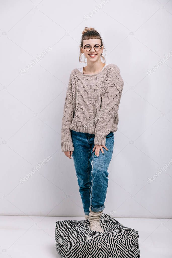 smiling girl putting leg on floor pillow and looking at camera