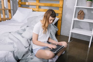 Kız Yatak odasında katta oturan ve dizüstü bilgisayar kullanarak 