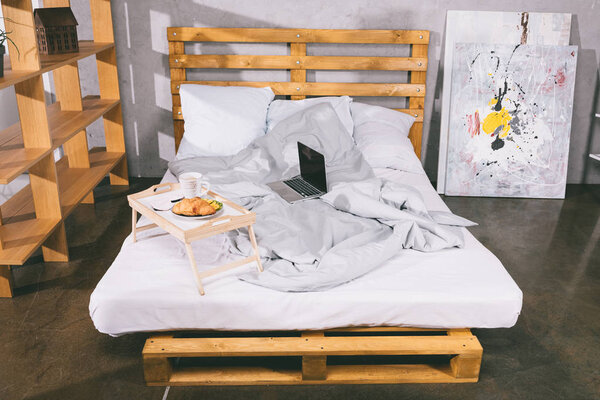 tray with breakfast and laptop on bed from pallets