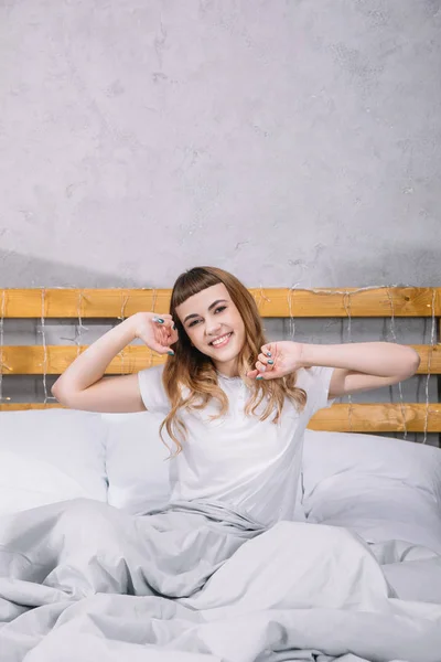 Gadis Bahagia Peregangan Tempat Tidur Pagi Hari Dan Melihat Kamera — Foto Stok Gratis
