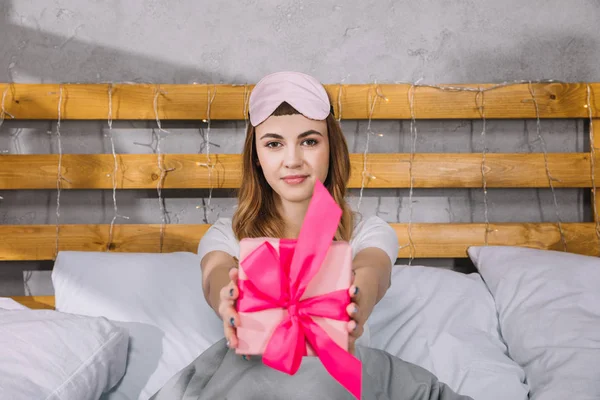 幸せな女の子のベッドに座っていると プレゼント ボックスを表示  — 無料ストックフォト