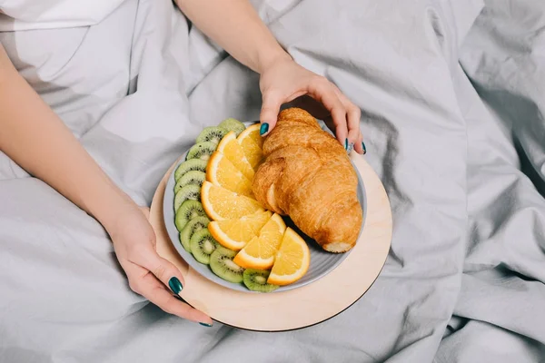 Imagem Cortada Menina Tomando Croissant Placa Cama — Fotografia de Stock Grátis